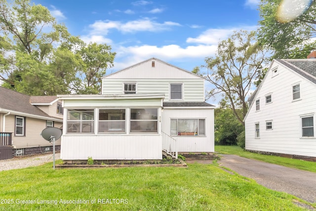 316 S Rosemary Ave, Lansing, MI 48917 - view of front of home with a sunroom, a shingled roof, and a front lawn