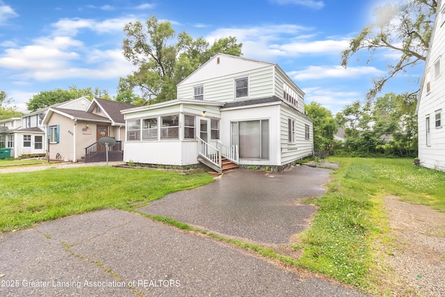 316 S Rosemary Ave, Lansing, MI 48917 - rear view of property featuring roof with shingles, a sunroom, and a yard