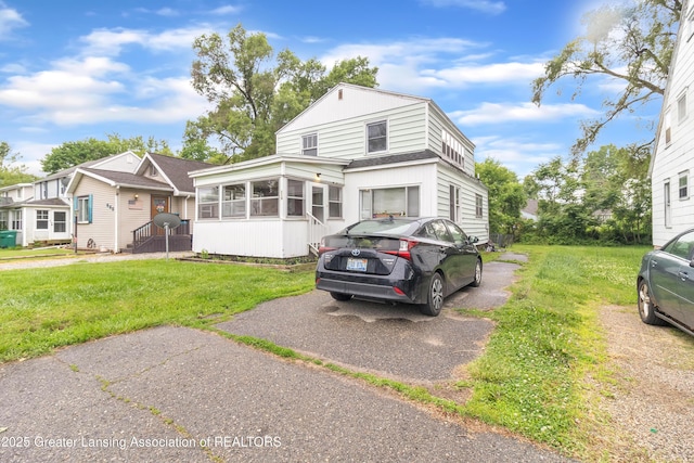 316 S Rosemary Ave, Lansing, MI 48917 - view of front of home featuring a sunroom, a shingled roof, and a front lawn