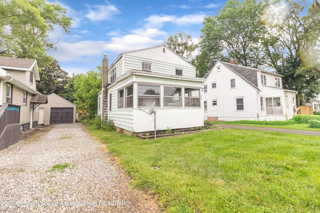 316 S Rosemary Ave, Lansing, MI 48917 - view of front of home featuring an outdoor structure, a chimney, a sunroom, a garage, and a front yard