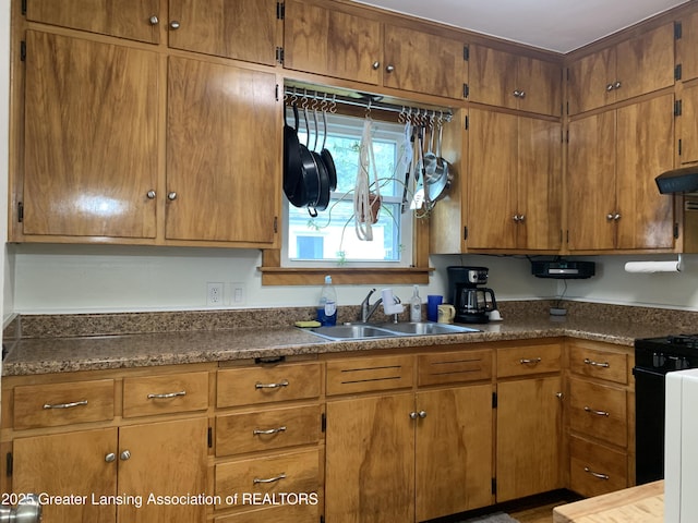 575 Brookland Blvd, Lansing, MI 48910 - kitchen with a sink, under cabinet range hood, brown cabinets, and gas range oven