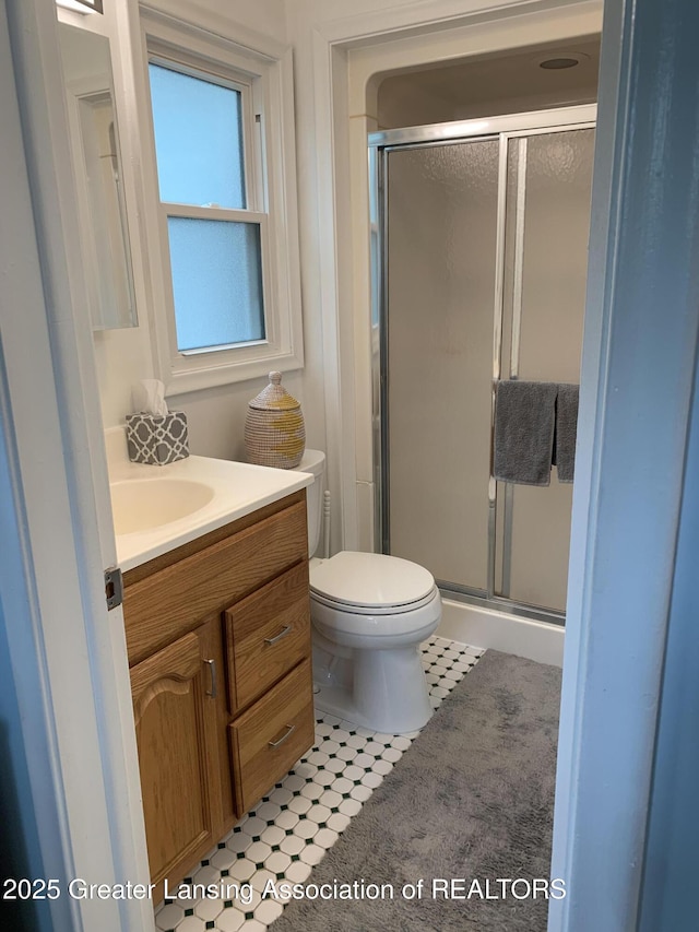 575 Brookland Blvd, Lansing, MI 48910 - bathroom featuring vanity, toilet, a stall shower, and tile patterned flooring