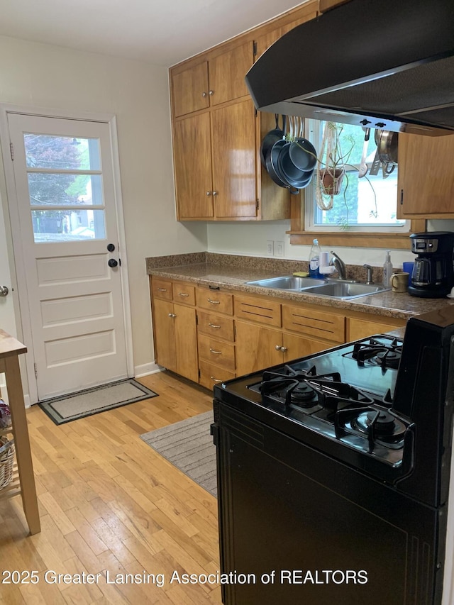 575 Brookland Blvd, Lansing, MI 48910 - kitchen with black range with gas stovetop, a sink, under cabinet range hood, and plenty of natural light