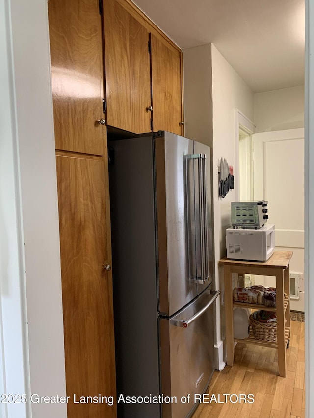 575 Brookland Blvd, Lansing, MI 48910 - kitchen featuring freestanding refrigerator, light wood-style floors, brown cabinetry, and white microwave