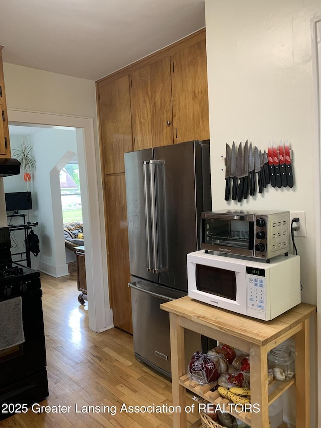 575 Brookland Blvd, Lansing, MI 48910 - kitchen featuring high quality fridge, white microwave, black range with gas stovetop, light wood finished floors, and extractor fan