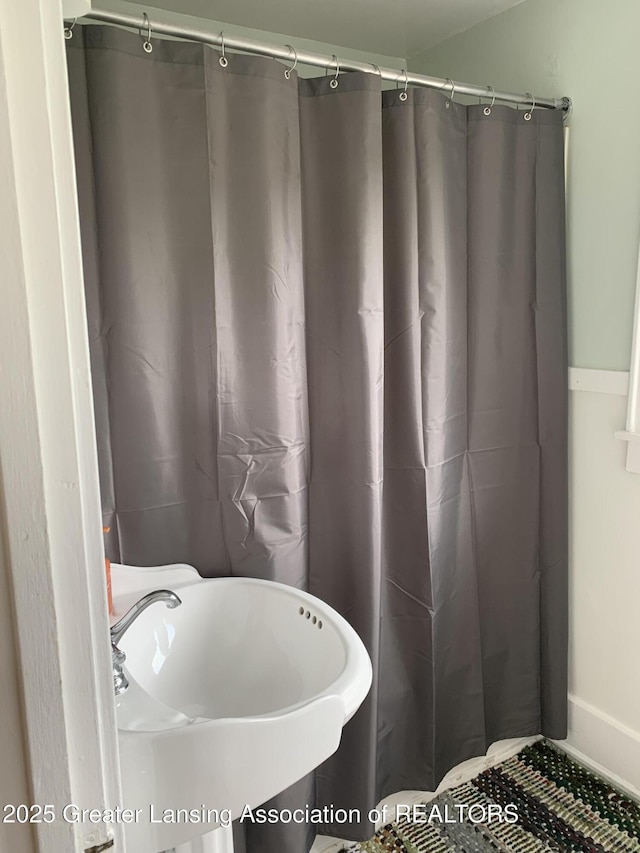 575 Brookland Blvd, Lansing, MI 48910 - bathroom with a sink, curtained shower, and baseboards