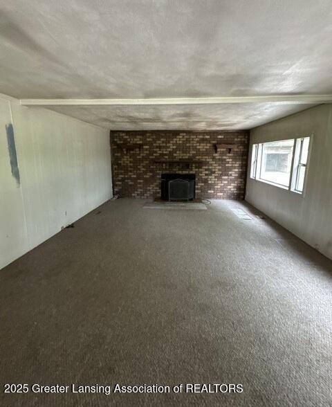 9882 W M 21, Ovid, MI 48866 - unfurnished living room featuring carpet flooring and a fireplace