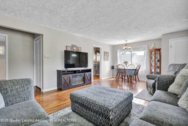 526 Detroit St, Portland, MI 48875 - living area with wood finished floors, baseboards, a chandelier, and a textured ceiling
