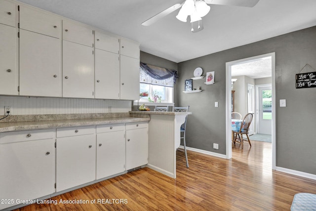 526 Detroit St, Portland, MI 48875 - kitchen with light wood finished floors, ceiling fan, white cabinetry, and light countertops