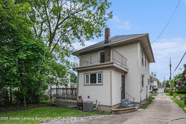 1417 W Ottawa St, Lansing, MI 48915 - back of house with a chimney, a balcony, central air condition unit, and a deck