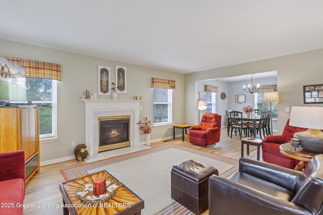 1990 S Waverly Rd, Eaton Rapids, MI 48827 - living area with light wood finished floors, a chandelier, a premium fireplace, and baseboards