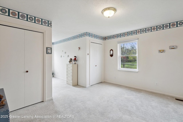 1990 S Waverly Rd, Eaton Rapids, MI 48827 - unfurnished bedroom featuring multiple closets, carpet flooring, and baseboards