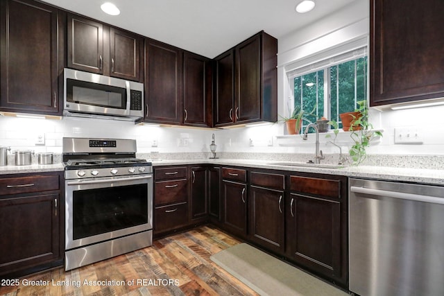 4269 Tamarack St, Holt, MI 48842 - kitchen featuring appliances with stainless steel finishes, a sink, wood finished floors, dark brown cabinetry, and recessed lighting