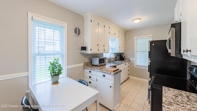 1451 Harvard Rd, East Lansing, MI 48823 - kitchen with stainless steel appliances, white cabinetry, a sink, light tile patterned floors, and light stone counters