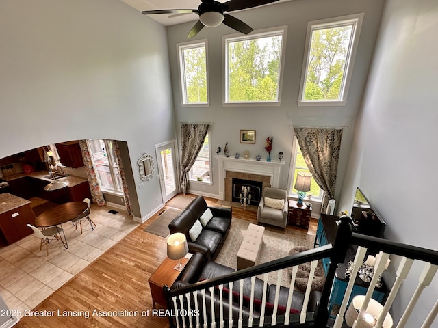 11195 W Herbison Rd, Eagle, MI 48822 - living room featuring ceiling fan, healthy amount of natural light, a high ceiling, a fireplace, and tile patterned flooring