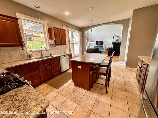 11195 W Herbison Rd, Eagle, MI 48822 - kitchen featuring a sink, stainless steel dishwasher, tasteful backsplash, arched walkways, and light stone counters