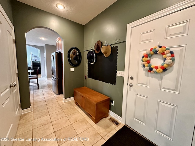 11195 W Herbison Rd, Eagle, MI 48822 - mudroom featuring arched walkways, light tile patterned floors, and baseboards