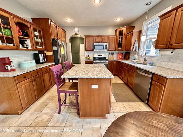 11195 W Herbison Rd, Eagle, MI 48822 - kitchen with stainless steel appliances, a sink, decorative backsplash, arched walkways, and brown cabinetry
