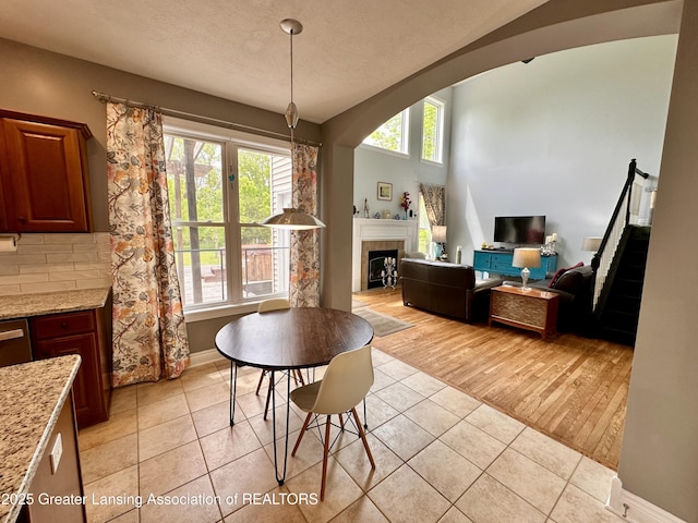 11195 W Herbison Rd, Eagle, MI 48822 - dining space featuring light tile patterned floors, baseboards, a fireplace, and a textured ceiling