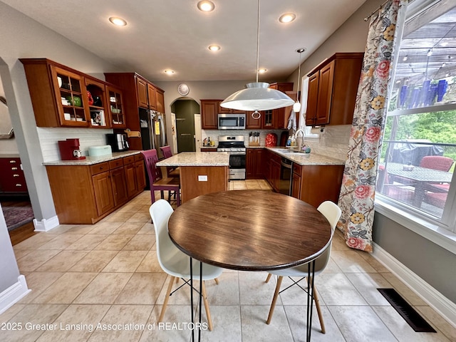 11195 W Herbison Rd, Eagle, MI 48822 - kitchen featuring stainless steel appliances, a sink, arched walkways, decorative backsplash, and recessed lighting