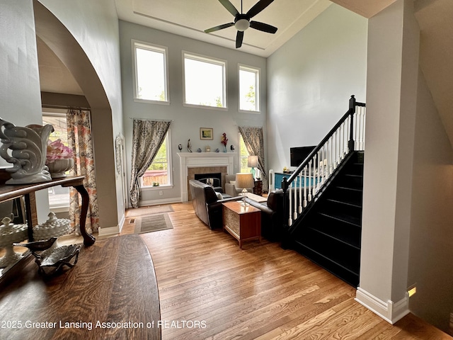 11195 W Herbison Rd, Eagle, MI 48822 - living room with a ceiling fan, high vaulted ceiling, light wood finished floors, arched walkways, and a tiled fireplace