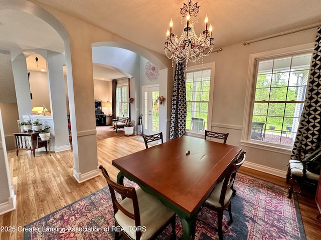 11195 W Herbison Rd, Eagle, MI 48822 - dining space with arched walkways, light wood-type flooring, a chandelier, and baseboards