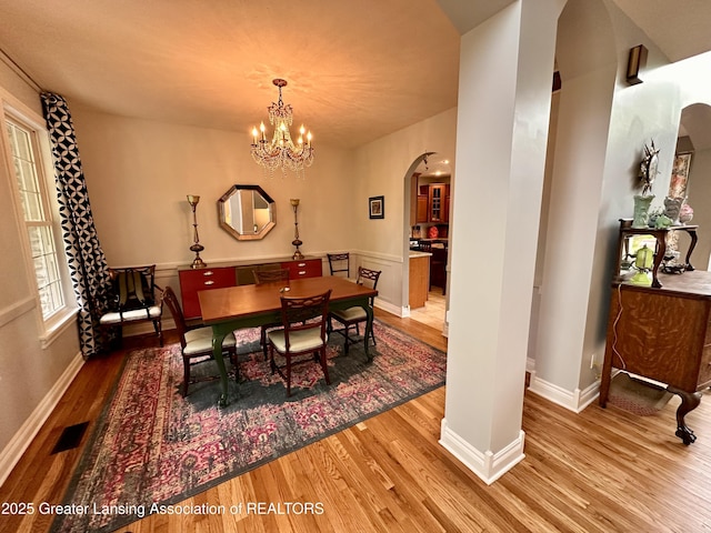 11195 W Herbison Rd, Eagle, MI 48822 - dining room featuring arched walkways, wood finished floors, baseboards, and a chandelier