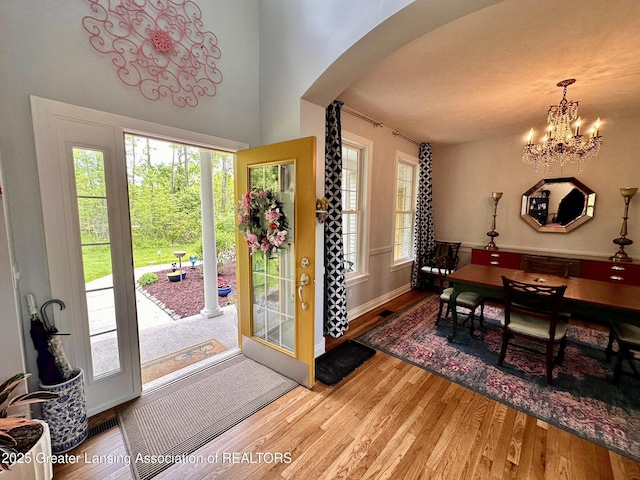 11195 W Herbison Rd, Eagle, MI 48822 - foyer entrance with arched walkways, wood finished floors, a chandelier, and baseboards