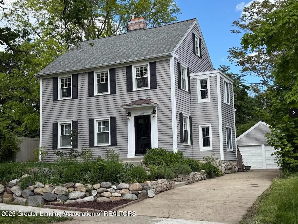 350 Kensington Rd, East Lansing, MI 48823 - colonial house with an outdoor structure, a chimney, a detached garage, and roof with shingles