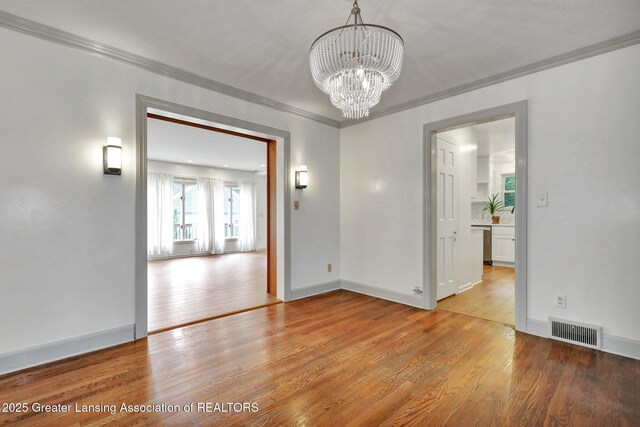 350 Kensington Rd, East Lansing, MI 48823 - spare room with ornamental molding, light wood finished floors, a chandelier, and baseboards