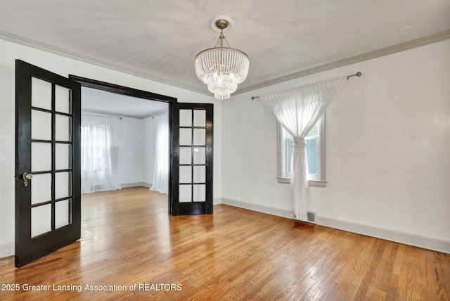 350 Kensington Rd, East Lansing, MI 48823 - unfurnished room with french doors, crown molding, plenty of natural light, a chandelier, and wood finished floors
