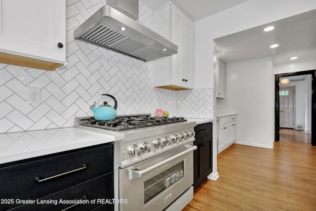 350 Kensington Rd, East Lansing, MI 48823 - kitchen featuring stainless steel stove, wall chimney range hood, light countertops, white cabinets, and recessed lighting