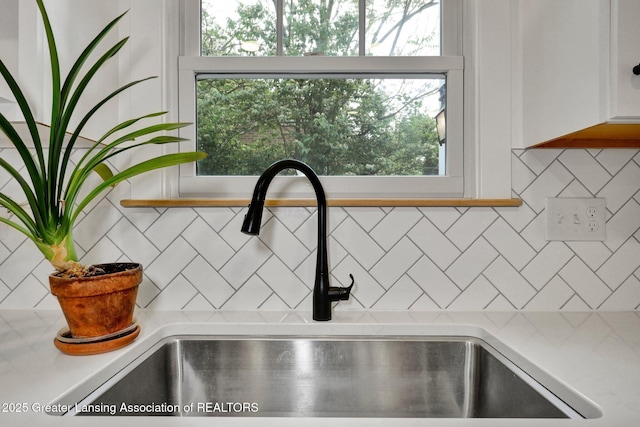 350 Kensington Rd, East Lansing, MI 48823 - kitchen view of a sink, light countertops, tasteful backsplash, and white cabinetry