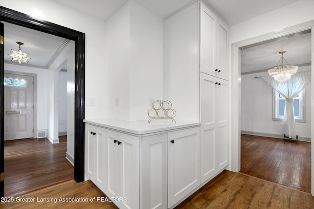 350 Kensington Rd, East Lansing, MI 48823 - hallway featuring a chandelier, dark wood finished floors, crown molding, and baseboards