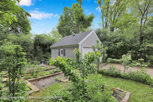 350 Kensington Rd, East Lansing, MI 48823 - view of home's exterior with a garden, roof with shingles, and a detached garage