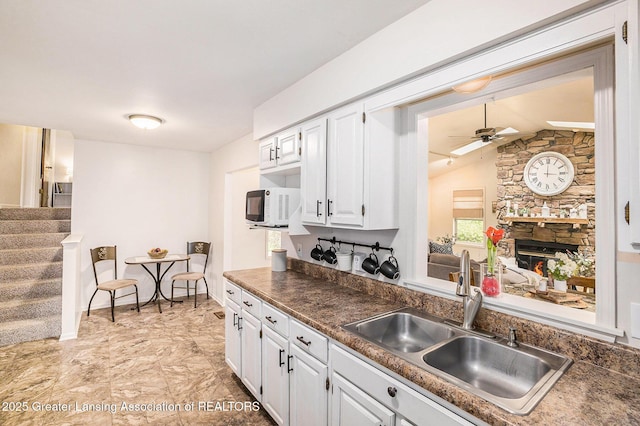 8450 Pineview Lake Dr, Linden, MI 48451 - kitchen featuring a sink, a ceiling fan, white cabinets, a fireplace, and white microwave