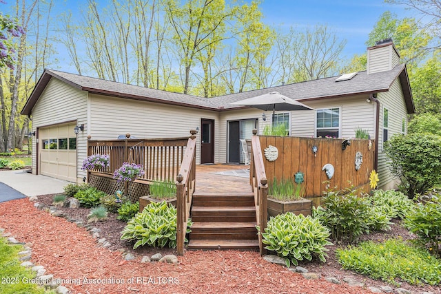8450 Pineview Lake Dr, Linden, MI 48451 - view of front of property with a deck, a chimney, concrete driveway, and a shingled roof