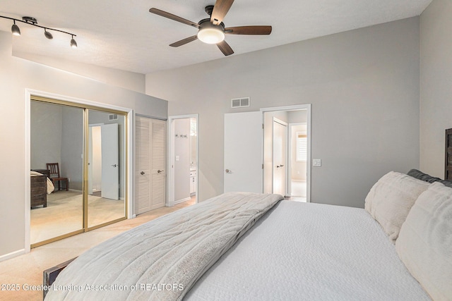1146 S Ridge Rd, Lansing, MI 48917 - bedroom with light carpet, vaulted ceiling, two closets, connected bathroom, and a ceiling fan
