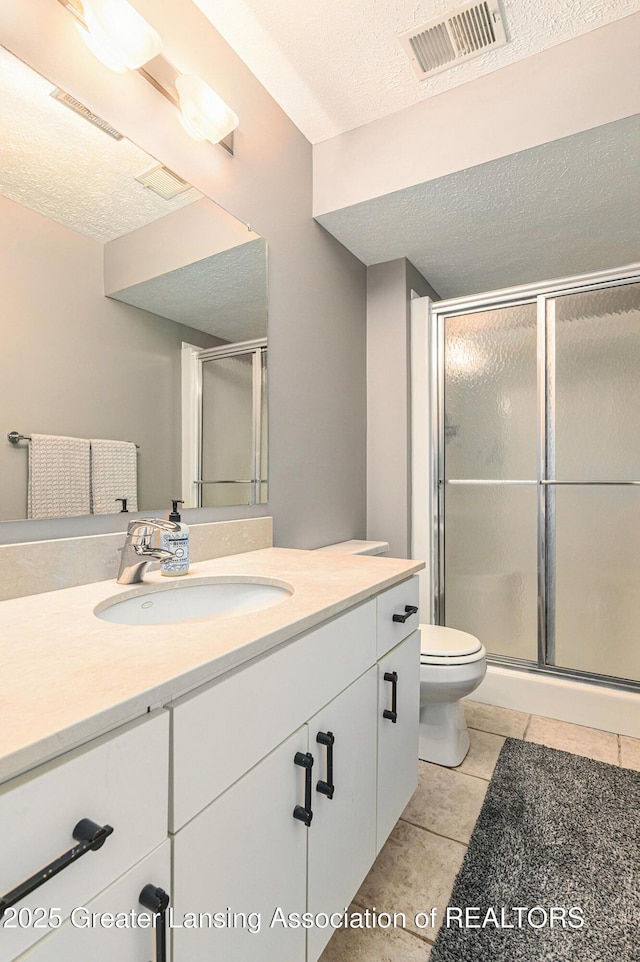 1146 S Ridge Rd, Lansing, MI 48917 - bathroom featuring vanity, a shower stall, toilet, a textured ceiling, and tile patterned floors
