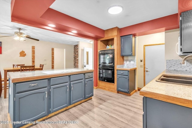 524 Dutch Hill Dr, Lansing, MI 48917 - kitchen featuring a sink, a ceiling fan, light wood-style floors, decorative backsplash, and white electric stovetop