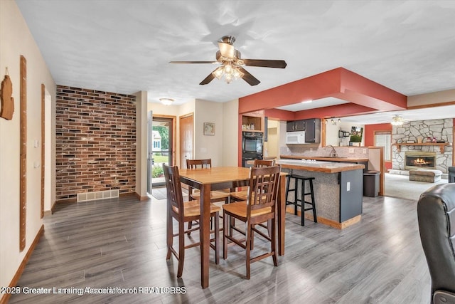 524 Dutch Hill Dr, Lansing, MI 48917 - dining room featuring wood finished floors, ceiling fan, baseboards, and a fireplace
