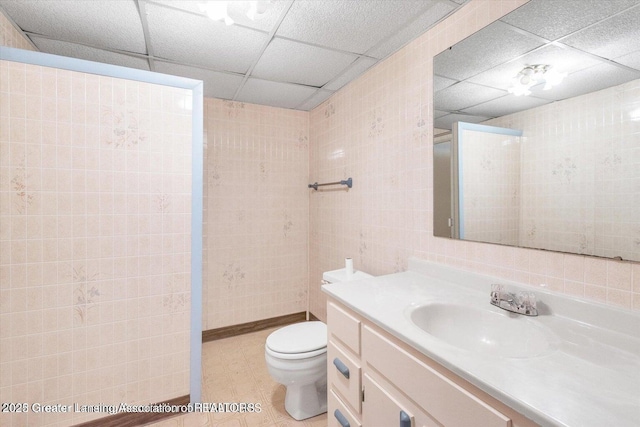 524 Dutch Hill Dr, Lansing, MI 48917 - bathroom featuring a paneled ceiling, vanity, toilet, and tile walls
