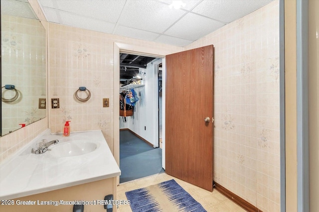 524 Dutch Hill Dr, Lansing, MI 48917 - bathroom with vanity, a walk in closet, a drop ceiling, and baseboards