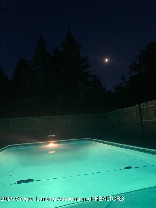 524 Dutch Hill Dr, Lansing, MI 48917 - pool at night featuring a fenced backyard