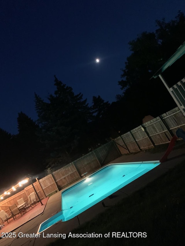 524 Dutch Hill Dr, Lansing, MI 48917 - pool at night featuring a fenced backyard and a water slide