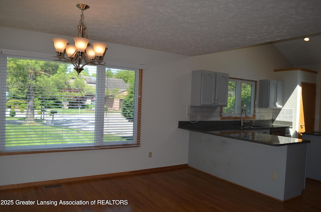 2397 Emerald Forest Cir Unit 26, East Lansing, MI 48823 - kitchen featuring dark countertops, wood finished floors, decorative backsplash, a chandelier, and a peninsula