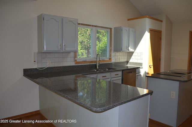 2397 Emerald Forest Cir Unit 26, East Lansing, MI 48823 - kitchen featuring stainless steel dishwasher, a peninsula, dark stone counters, backsplash, and vaulted ceiling