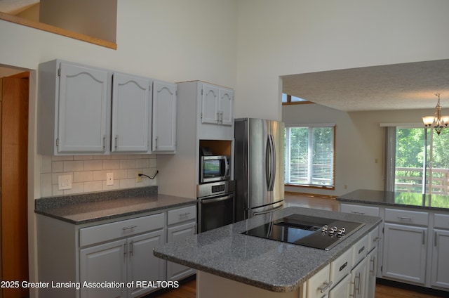 2397 Emerald Forest Cir Unit 26, East Lansing, MI 48823 - kitchen featuring appliances with stainless steel finishes, a center island, tasteful backsplash, a high ceiling, and a chandelier