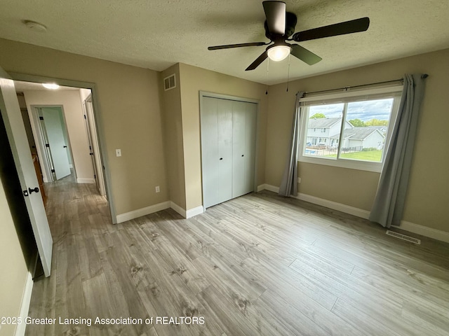 1512 Lindy Dr, Lansing, MI 48917 - unfurnished bedroom with light wood finished floors, a closet, a textured ceiling, baseboards, and ceiling fan
