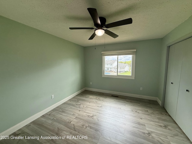 1512 Lindy Dr, Lansing, MI 48917 - unfurnished bedroom with a textured ceiling, a closet, light wood-style flooring, baseboards, and ceiling fan